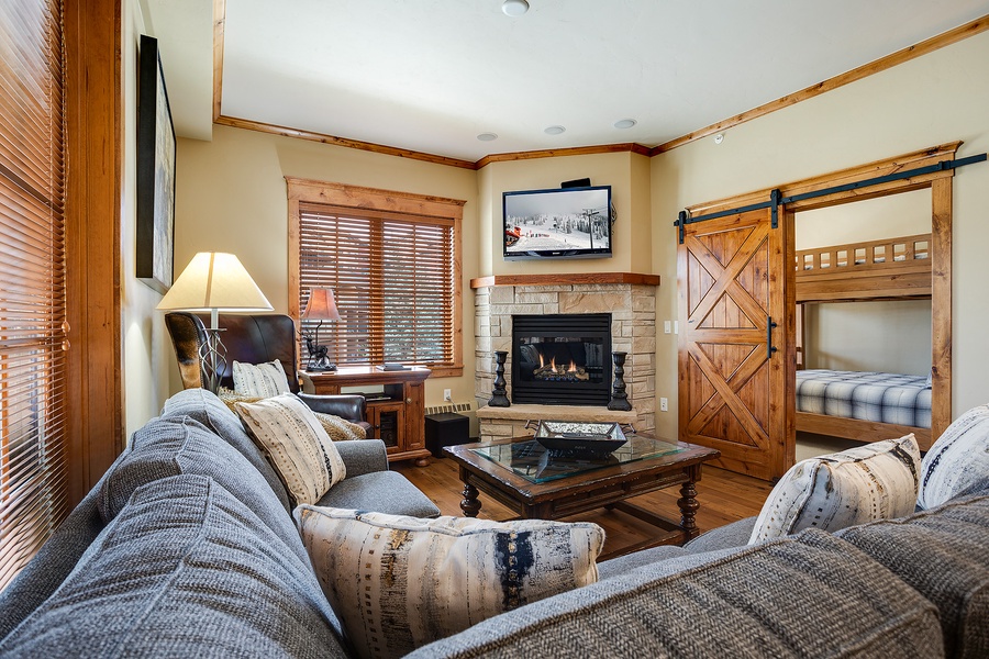 Curl up on plush sofas beside your own stone fireplace, where rustic wood accents and a cozy bunk nook create the perfect mountain retreat for relaxing after adventure.