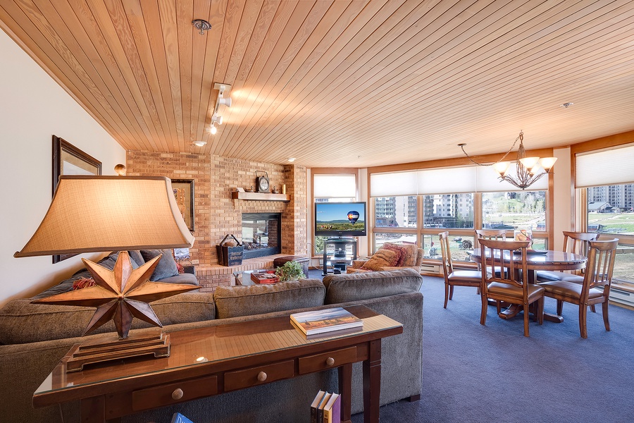 Unwind in your spacious living area with warm wood ceilings, cozy fireplace, and panoramic water views framing every moment of relaxation and togetherness.