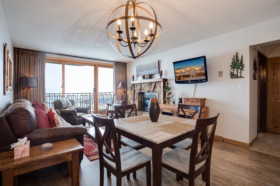 Your open-concept living space blends comfort with mountain charm—gather around the dining table, relax by the stone fireplace, or step out onto your balcony to enjoy breathtaking views.