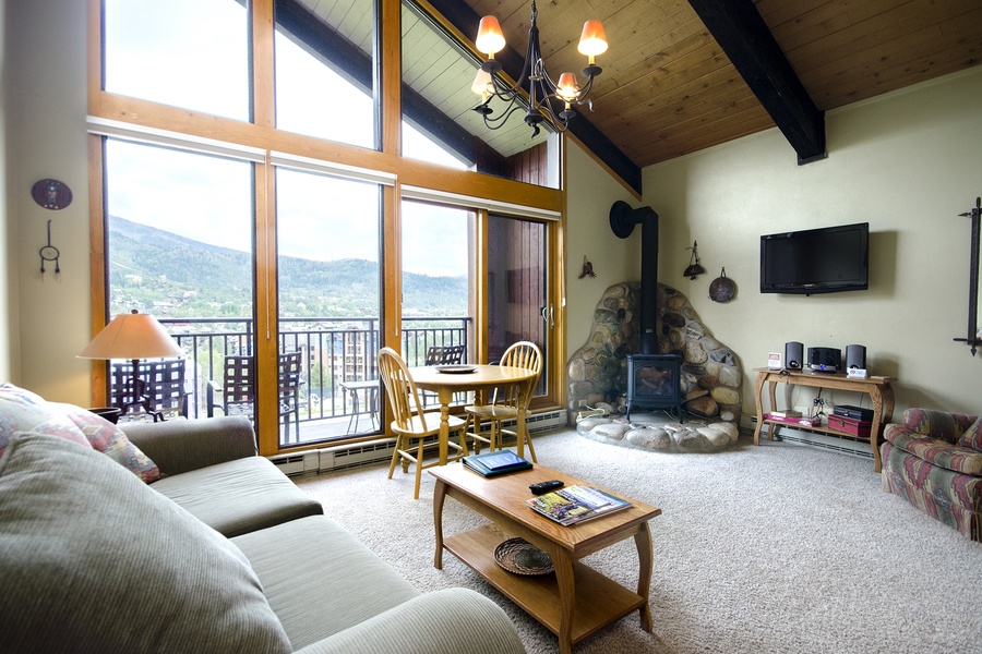 Settle into your spacious living room with soaring ceilings, cozy fireplace, and breathtaking mountain views through floor-to-ceiling windows. Your perfect mountain getaway awaits.