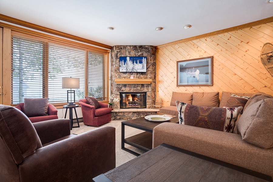 Sink into plush seating by your crackling stone fireplace, with warm pine walls and mountain light streaming in—your cozy alpine retreat awaits.