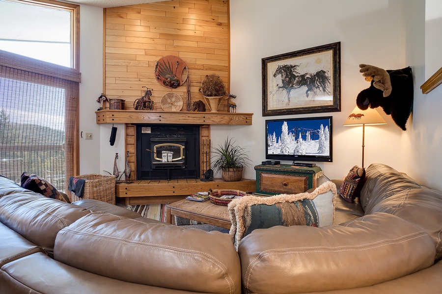 Sink into plush leather sofas by the crackling wood-burning fireplace, where rustic western charm meets cozy mountain comfort in your inviting living room retreat.