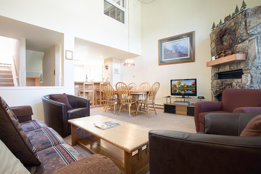 Gather with loved ones in your spacious living area, where soaring ceilings and a stunning stone fireplace create a warm, inviting atmosphere for memorable conversations and cozy evenings together.