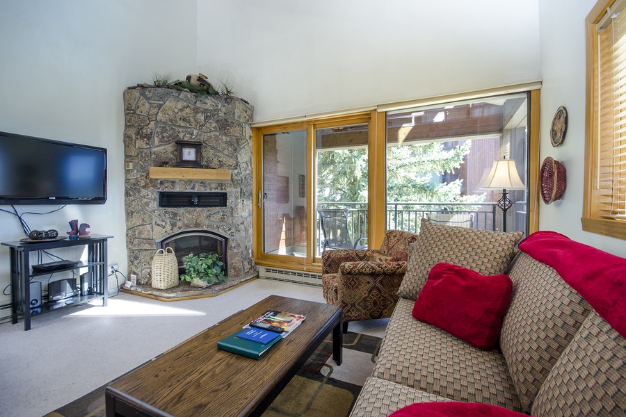Relax in your spacious living room with a cozy stone fireplace, mountain views through sliding glass doors, and comfortable seating—perfect for unwinding after a day of adventure.