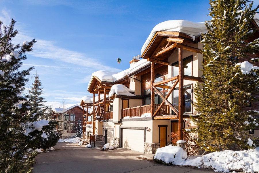 A stunning mountain chalet nestled among snow-dusted pines, featuring warm timber accents and private balconies with breathtaking alpine surroundings for a peaceful winter retreat.