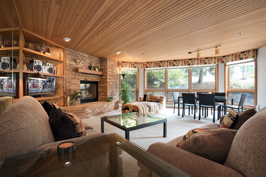 Cozy living space with plush seating, a warm fireplace, and sunlit windows overlooking the peaceful outdoors—your perfect retreat for relaxing evenings and family gatherings.