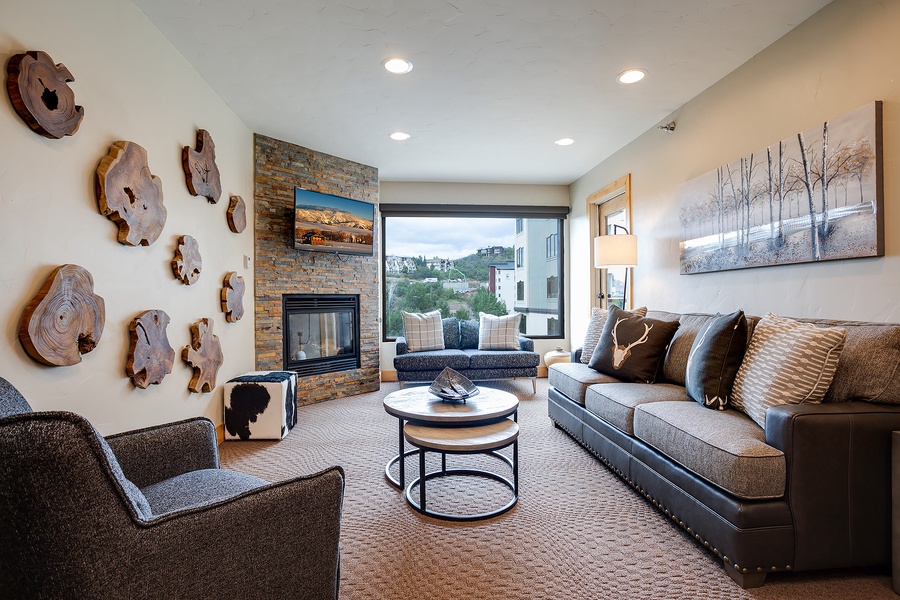 Settle into your modern living room where warm textures and mountain views meet. A cozy fireplace, plush seating, and natural wood accents create your perfect retreat after a day exploring.
