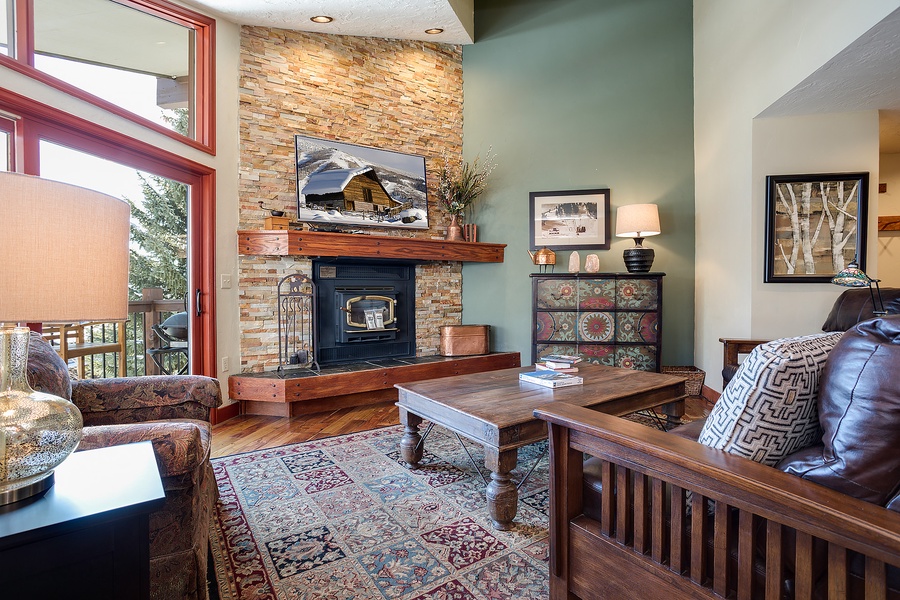 Sink into cozy seating by the warm stone fireplace while taking in the mountain views through soaring windows. Your perfect alpine retreat awaits with rustic charm and comfortable furnishings.