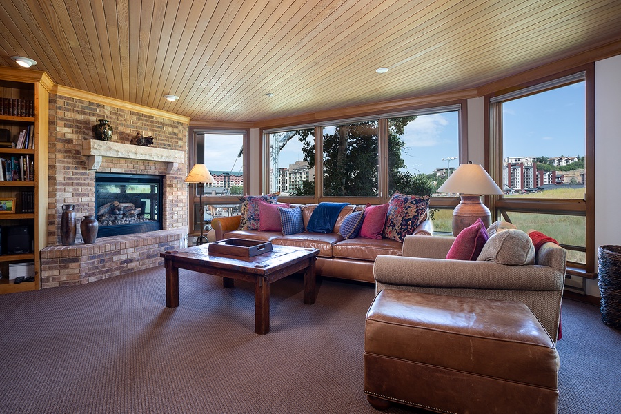 Relax in your bright living room with plush leather seating, a warm fireplace, and sweeping city views through expansive windows—your perfect retreat after a day exploring.