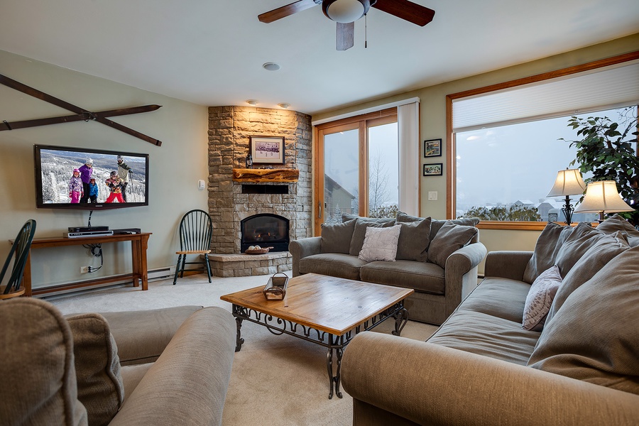 Sink into plush seating beside a glowing stone fireplace as mountain and valley views stretch beyond your windows, blending warmth and natural beauty.
