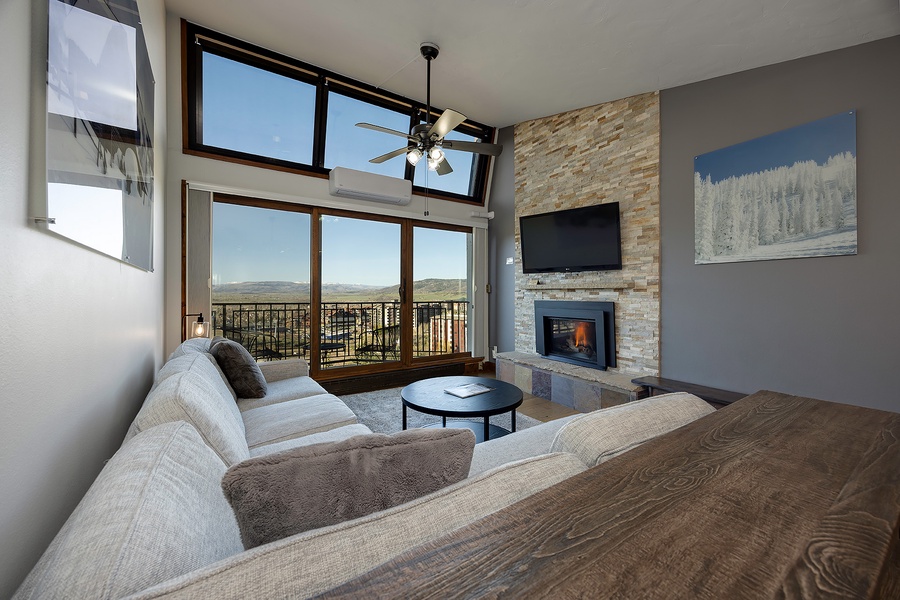Sink into plush seating and soak up mountain views through floor-to-ceiling windows. The stone fireplace adds warmth while you unwind in your stylish retreat.
