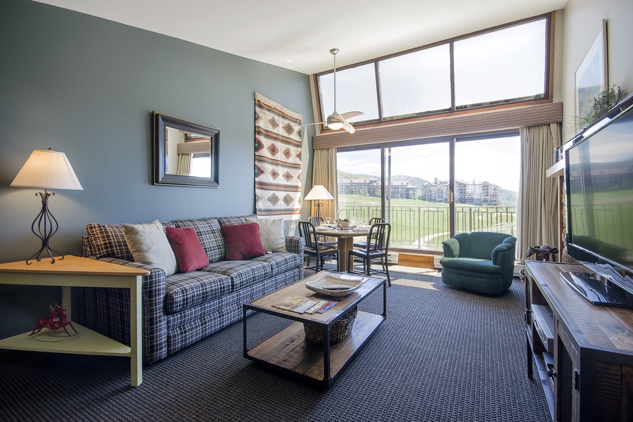 Settle into your cozy living room and enjoy expansive golf course views through floor-to-ceiling windows, perfect for unwinding after a day of mountain adventures.