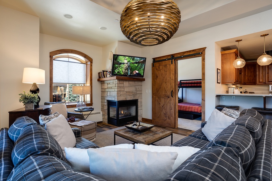 Unwind in your welcoming living area, where plush plaid sofas, a cozy fireplace, and a unique statement chandelier create the perfect mountain retreat ambiance for your stay.