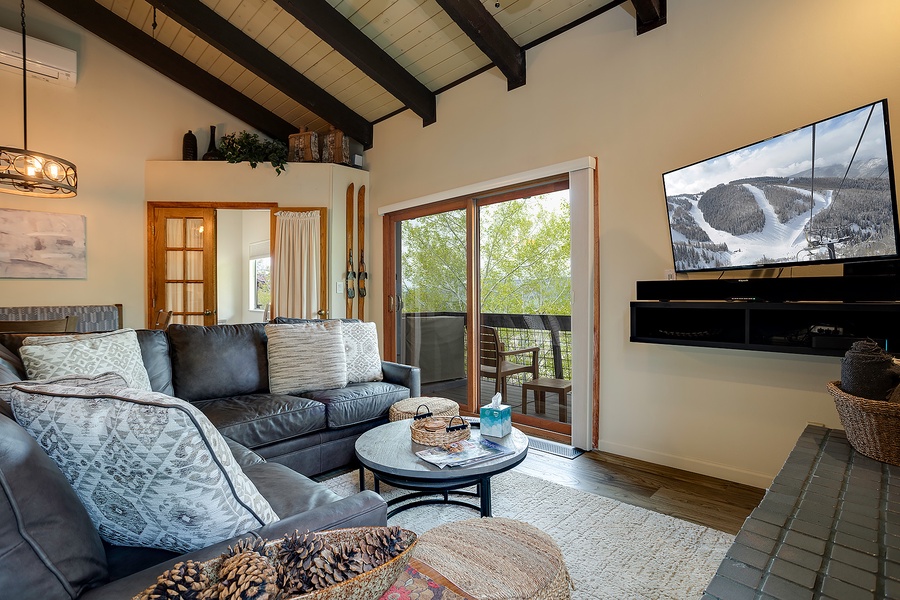 Relax in your spacious living room with exposed beam ceilings, where you can unwind on plush sofas, enjoy mountain views through the balcony doors, and catch your favorite shows on the large flat-screen TV.