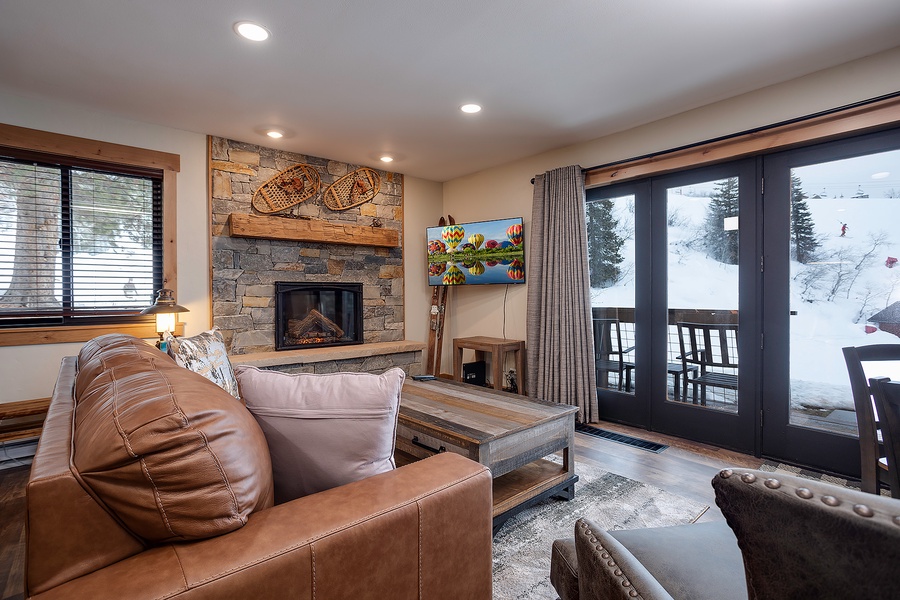 Curl up by the stone fireplace with your favorite book, or enjoy ski slope views from the balcony—this cozy living room invites you to unwind in mountain luxury.