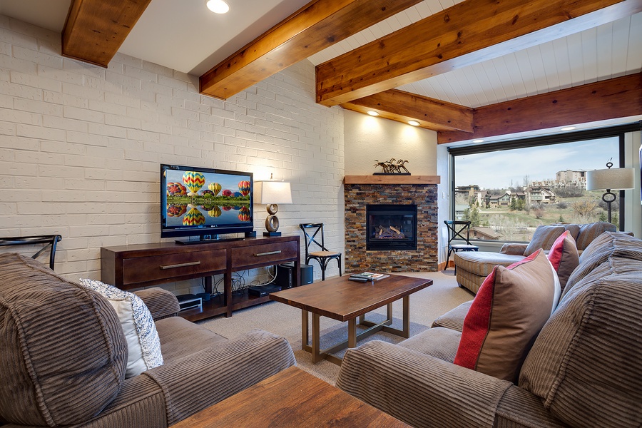 Unwind in your inviting living space, where exposed wood beams frame plush sofas, a cozy fireplace, and sweeping views that make every moment feel like a true getaway.