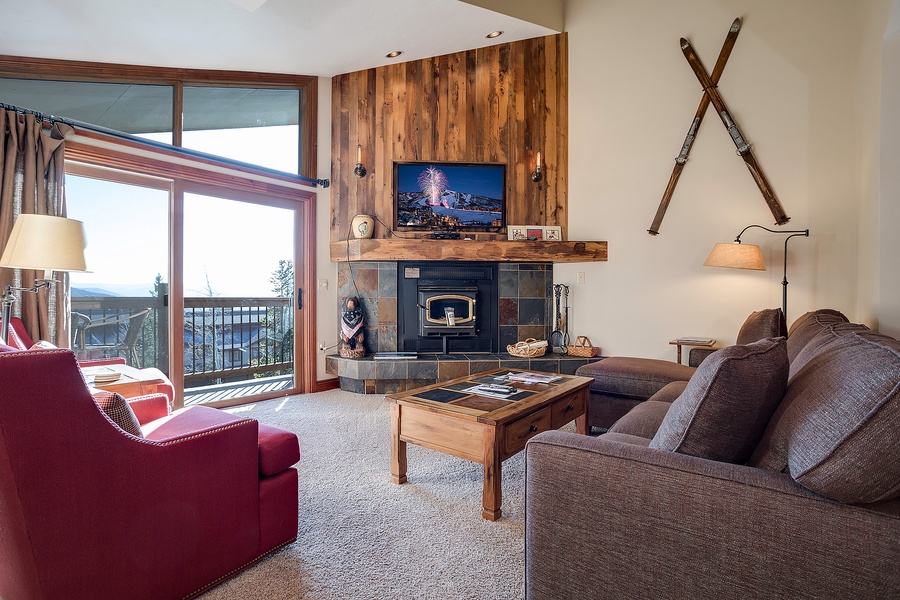 Unwind in your inviting living space featuring a cozy fireplace, plush seating, and a private balcony with mountain views—your perfect alpine retreat.