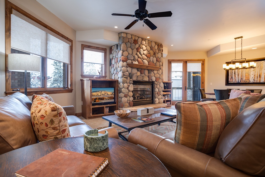Sink into plush leather sofas in your cozy living room, where a stunning river-rock fireplace and mountain views through expansive windows create the perfect retreat after a day of adventure.