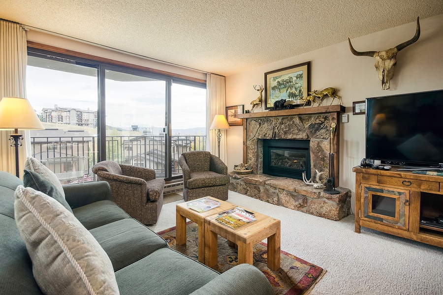 Settle into this inviting living room where rustic charm meets comfort. Relax by the stone fireplace, enjoy your favorite shows, and take in sweeping views from your private balcony.