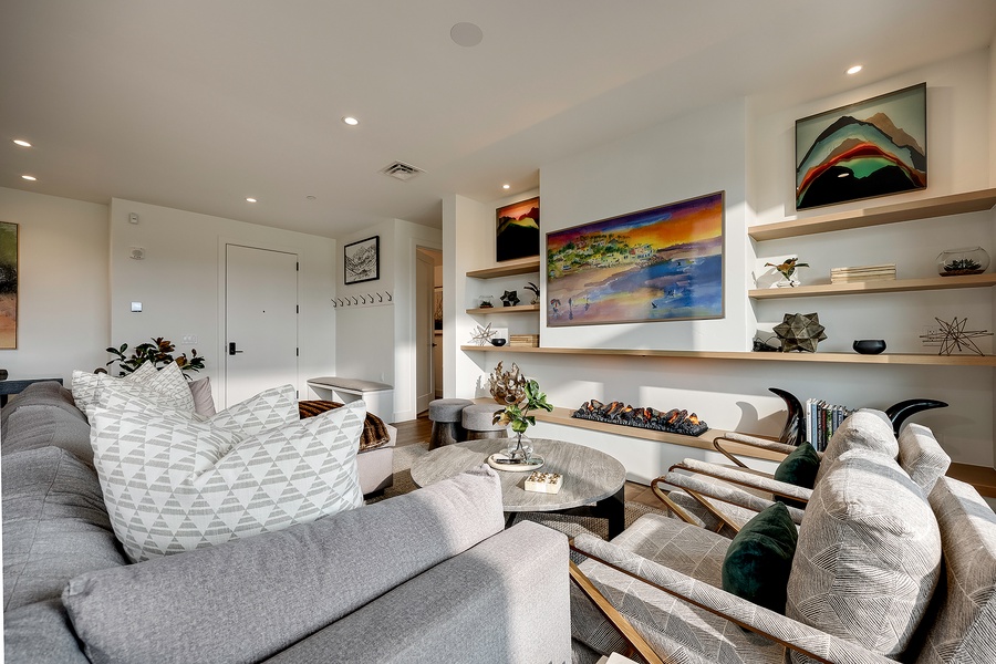 Settle into plush, modern seating where thoughtful design meets comfort. Open shelving displays curated pieces, while artwork and soft lighting create a welcoming retreat for your relaxation.
