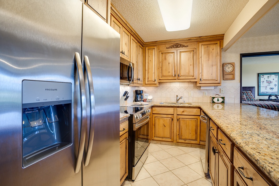 Your fully equipped kitchen features modern stainless steel appliances, elegant granite countertops, and warm wood cabinetry—everything you need to prepare your favorite meals in comfort.