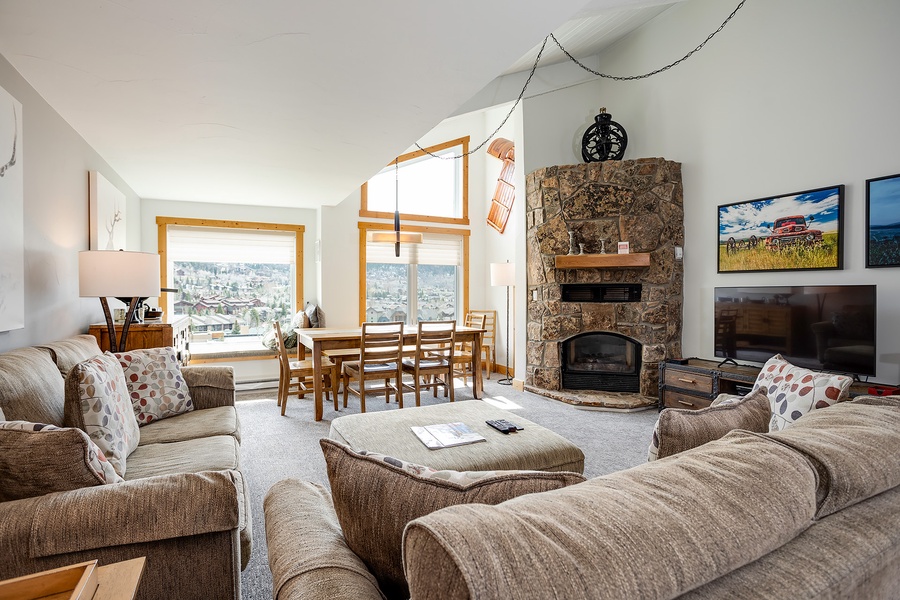 Unwind in this bright, spacious living room with cozy seating, a stone fireplace, and stunning mountain views—your perfect alpine retreat awaits.