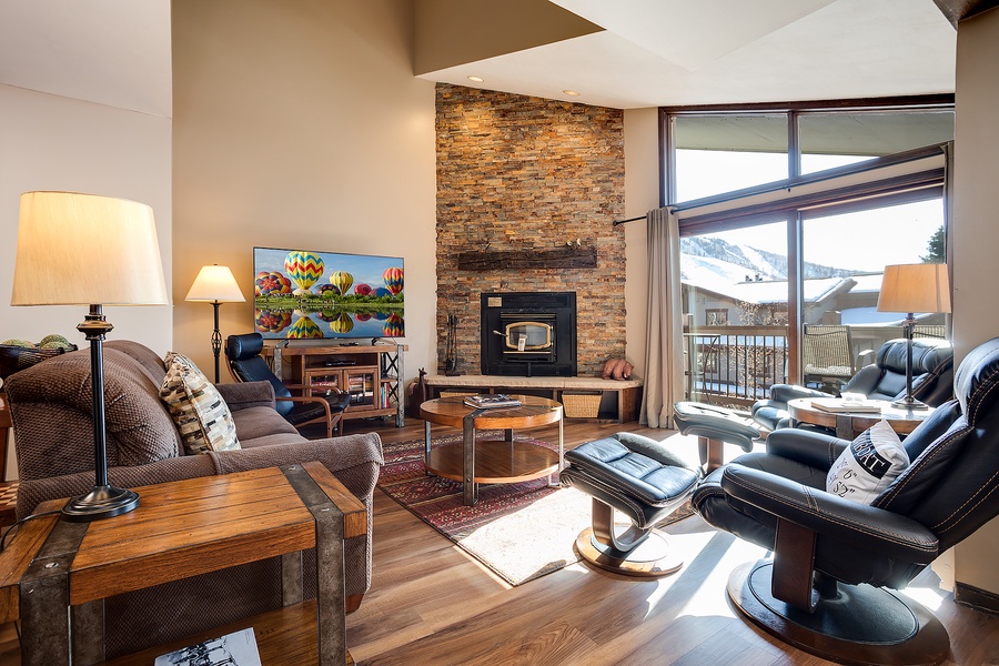 Unwind in your inviting living room with soaring ceilings, a cozy stone fireplace, and sweeping mountain views through expansive windows. Your perfect retreat after a day of adventure.