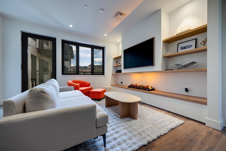 Unwind in your chic living room with cozy seating, modern fireplace, and open shelving for personal touches. Large windows frame mountain vistas, while warm lighting and natural textures invite relaxation.