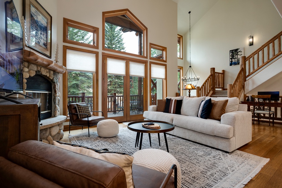 Unwind in your bright and spacious living room, where soaring ceilings and floor-to-ceiling windows frame serene forest views. Sink into plush seating by the stone fireplace and let natural light fill your mountain retreat.