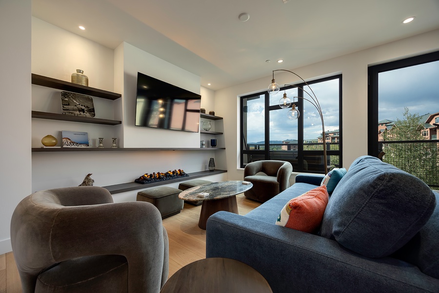Sink into plush seating and let the day melt away in your elegant living space, where modern design meets natural light through floor-to-ceiling windows overlooking the surrounding area.