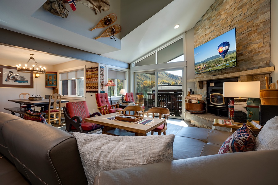 Settle into your cozy living space with mountain views through tall windows, a warm fireplace, and inviting seating where you can unwind and soak in the charm.