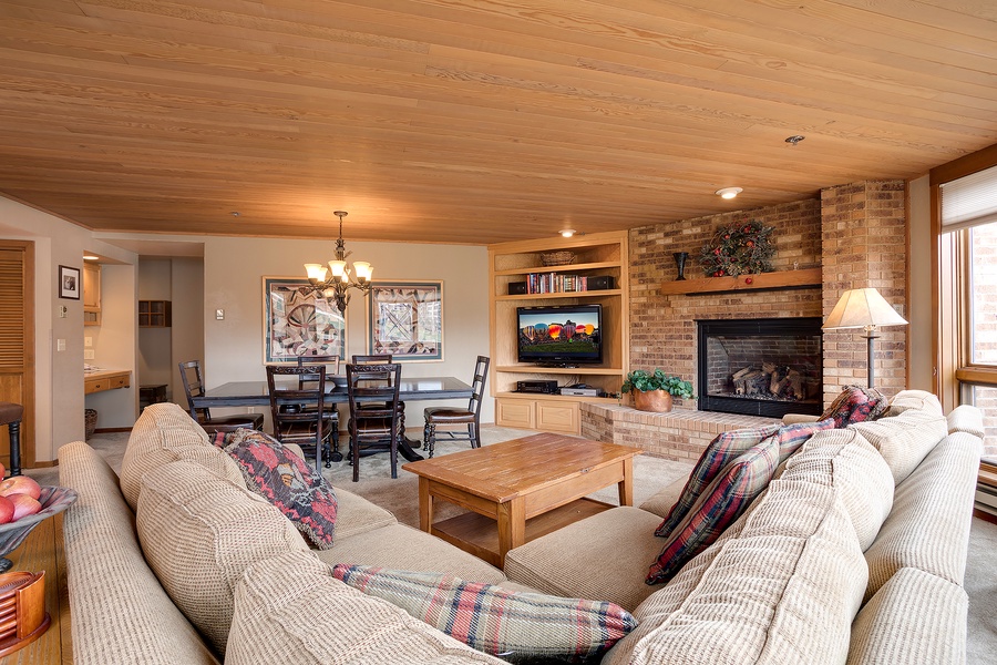 Picture yourself relaxing in this spacious living room with its warm wood ceilings, cozy fireplace, and comfy sofas—perfect for gathering with loved ones or unwinding after a day of adventure.