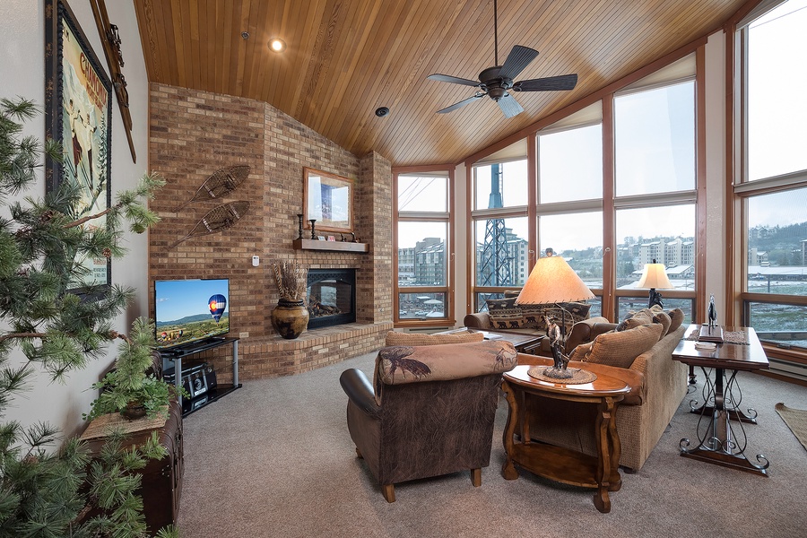 Curl up in your cozy living room with soaring wood ceilings, a warm fireplace, and panoramic windows framing stunning lakeside and mountain views—your perfect retreat awaits.