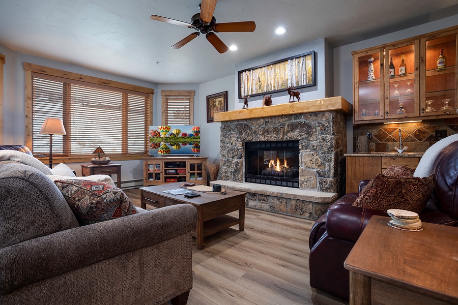 Unwind in your cozy living room with plush seating, a warm stone fireplace, and charming mountain-inspired décor that invites you to relax and feel at home.