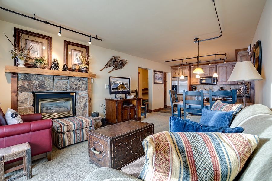 Settle into your cozy mountain retreat with rustic charm: a crackling stone fireplace, inviting seating, and an open kitchen ready for your alpine adventures.