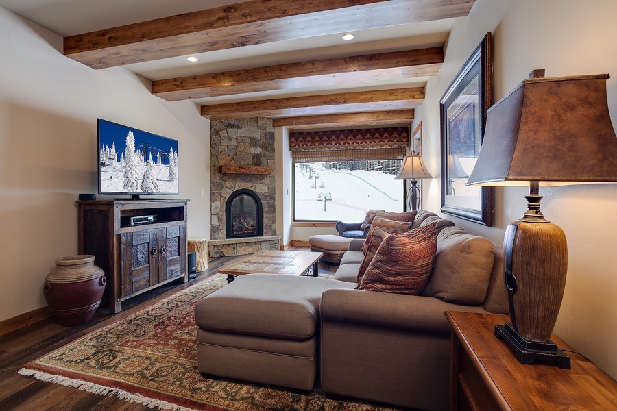 Unwind in your mountain retreat with vaulted wood-beam ceilings, a stone fireplace, and ski slope views—your perfect après-ski sanctuary awaits.