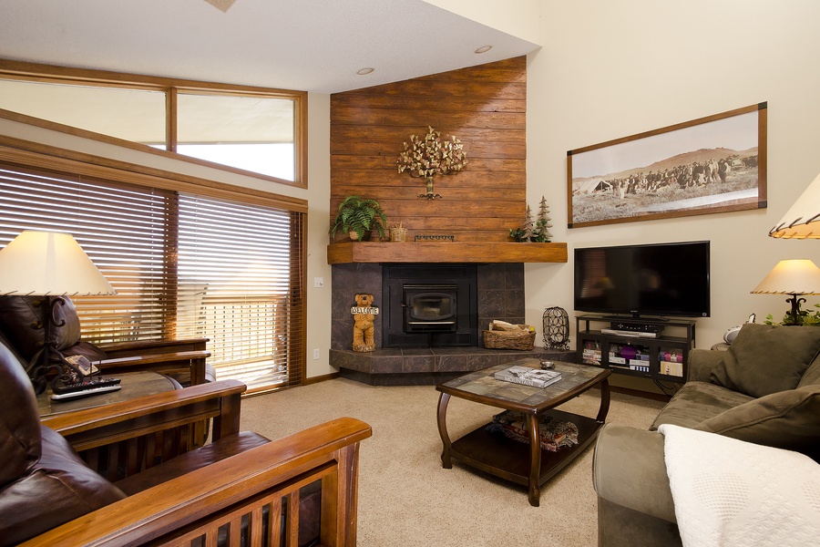 Gather in your cozy living room where mountain-rustic charm meets comfort—a wood-accented fireplace, plush seating, and entertainment center invite relaxing evenings after days on the slopes.