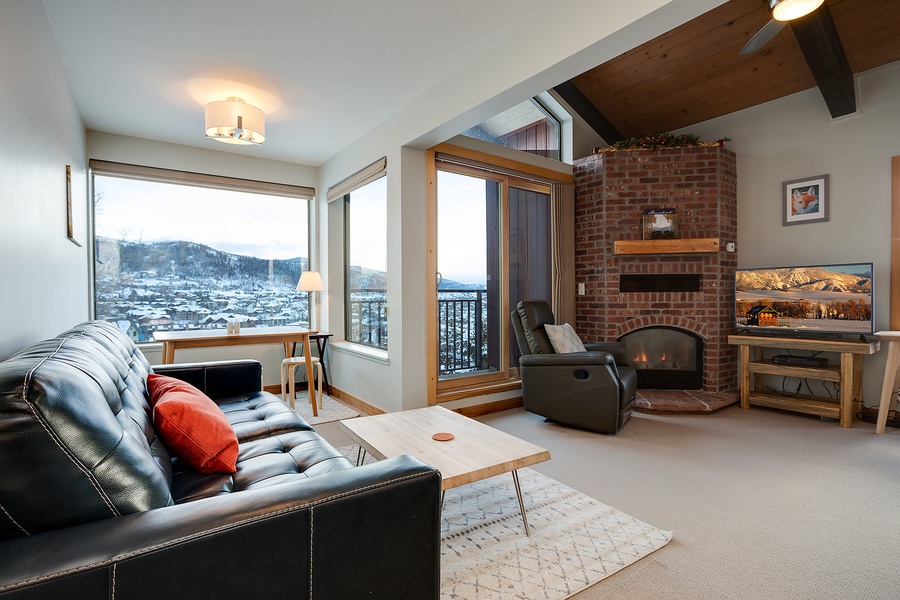 Cozy living room with a warm fireplace, mountain views, and vaulted ceilings—your perfect retreat after a day of adventure.