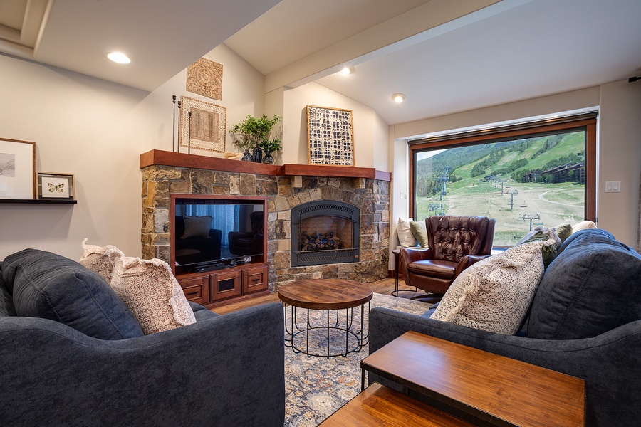 Unwind in your inviting living room, where plush sofas face a stone fireplace and mountain vistas—perfect for cozy evenings after a day of adventure.