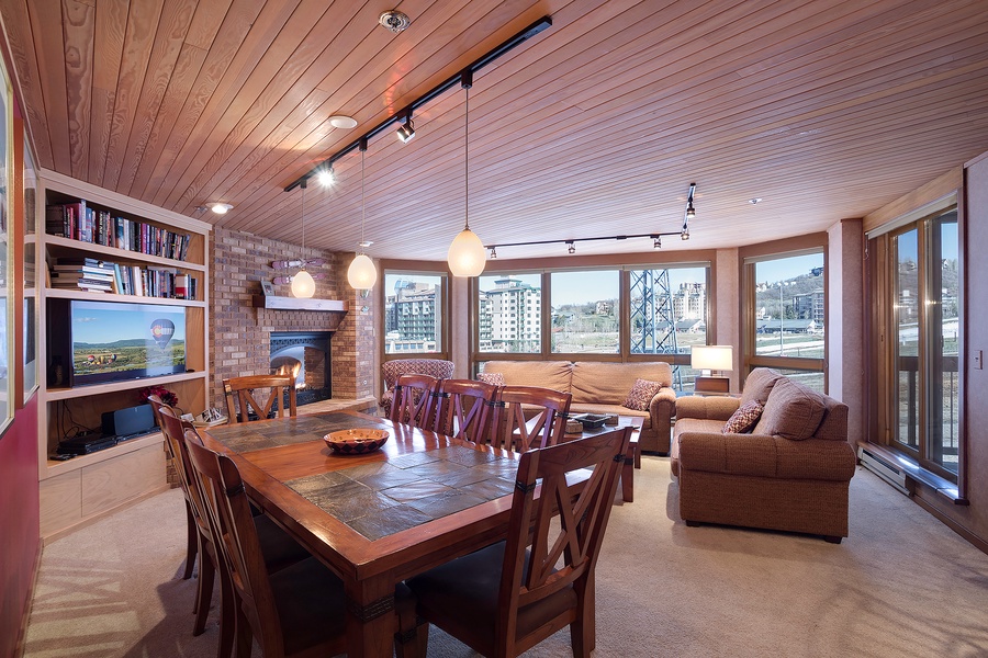 Gather around the handsome dining table while natural light pours through expansive windows. Relax by the cozy fireplace in this inviting space designed for memorable evenings together.