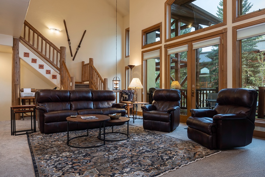 Sink into plush leather seating in your spacious living room, where floor-to-ceiling windows frame lush forest views and a warm, inviting atmosphere welcomes you home.