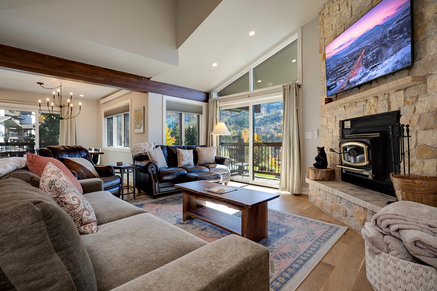 Unwind in this bright, open living space with soaring ceilings, plush seating, and a stone fireplace. Large windows frame stunning mountain views, inviting natural light into your cozy retreat.