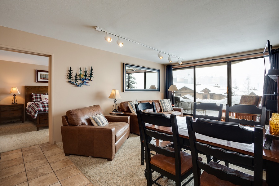 Picture yourself unwinding on the plush leather sofa, natural light streaming through expansive windows framing snowy mountain views, creating your perfect après-ski retreat.