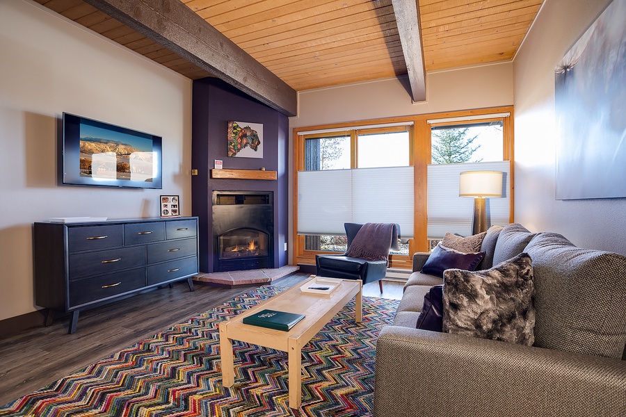 Sink into plush seating by your private fireplace, where warm wood tones and mountain light create your perfect retreat after a day of adventure.
