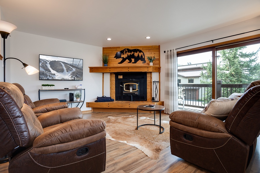 Sink into plush recliners facing your wood-burning fireplace. The space flows to a private balcony framed by forest views—perfect for unwinding after mountain adventures.