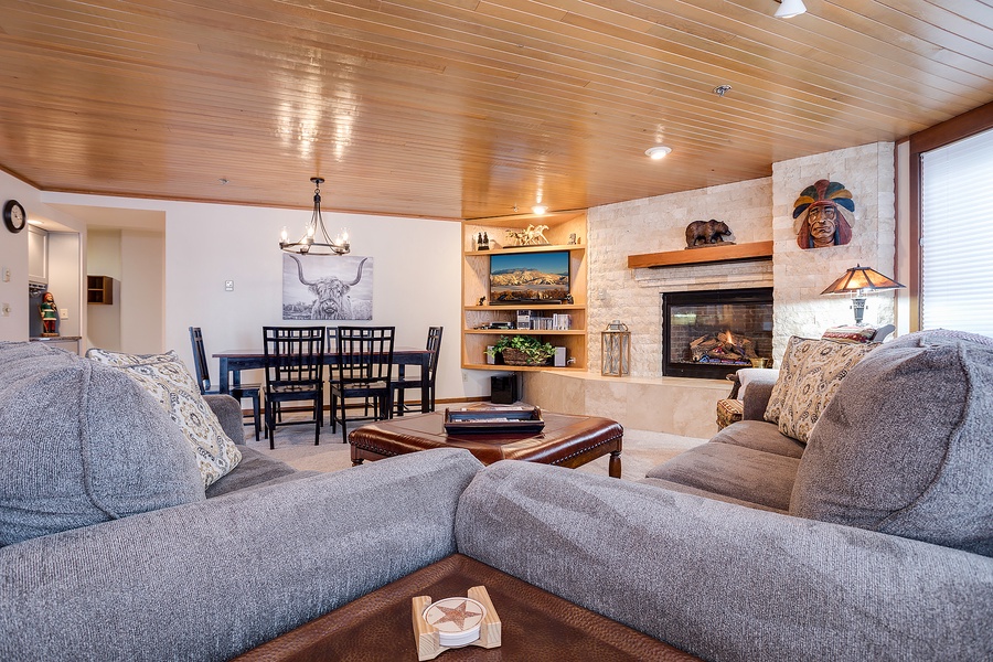 Unwind in your spacious open-concept living area with cozy sofas, a warm stone fireplace, and rustic Western decor that invites relaxation after a day exploring.