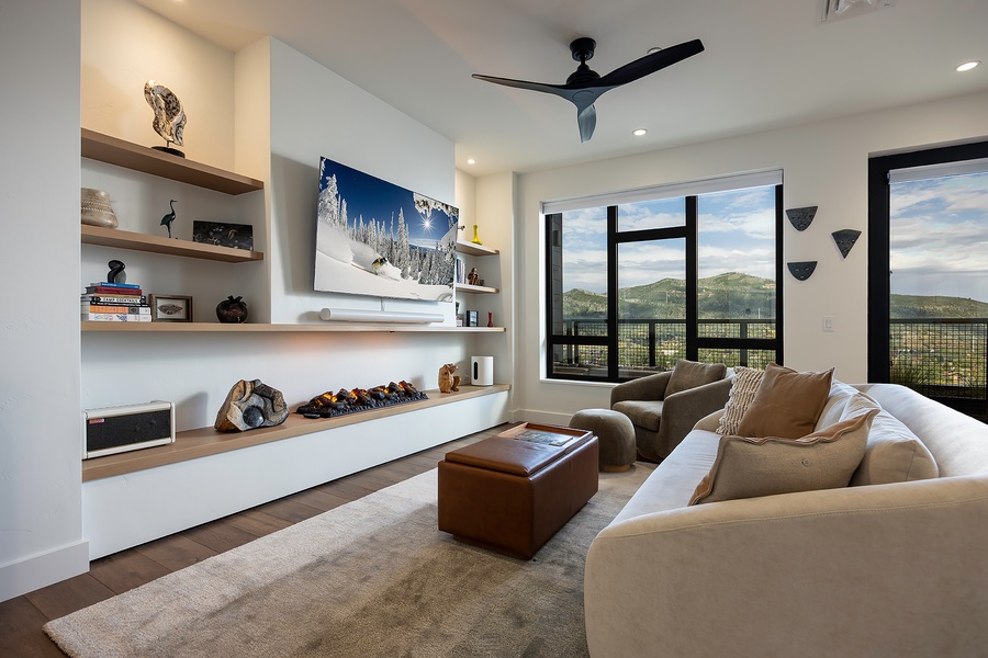 Sink into plush seating in this modern living room where panoramic mountain views through floor-to-ceiling windows create your perfect mountain retreat backdrop.