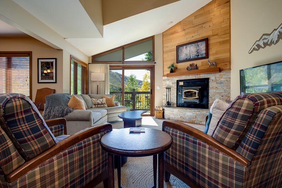 Sink into plush seating by your cozy stone fireplace, where vaulted ceilings and mountain views through expansive windows create your perfect retreat.