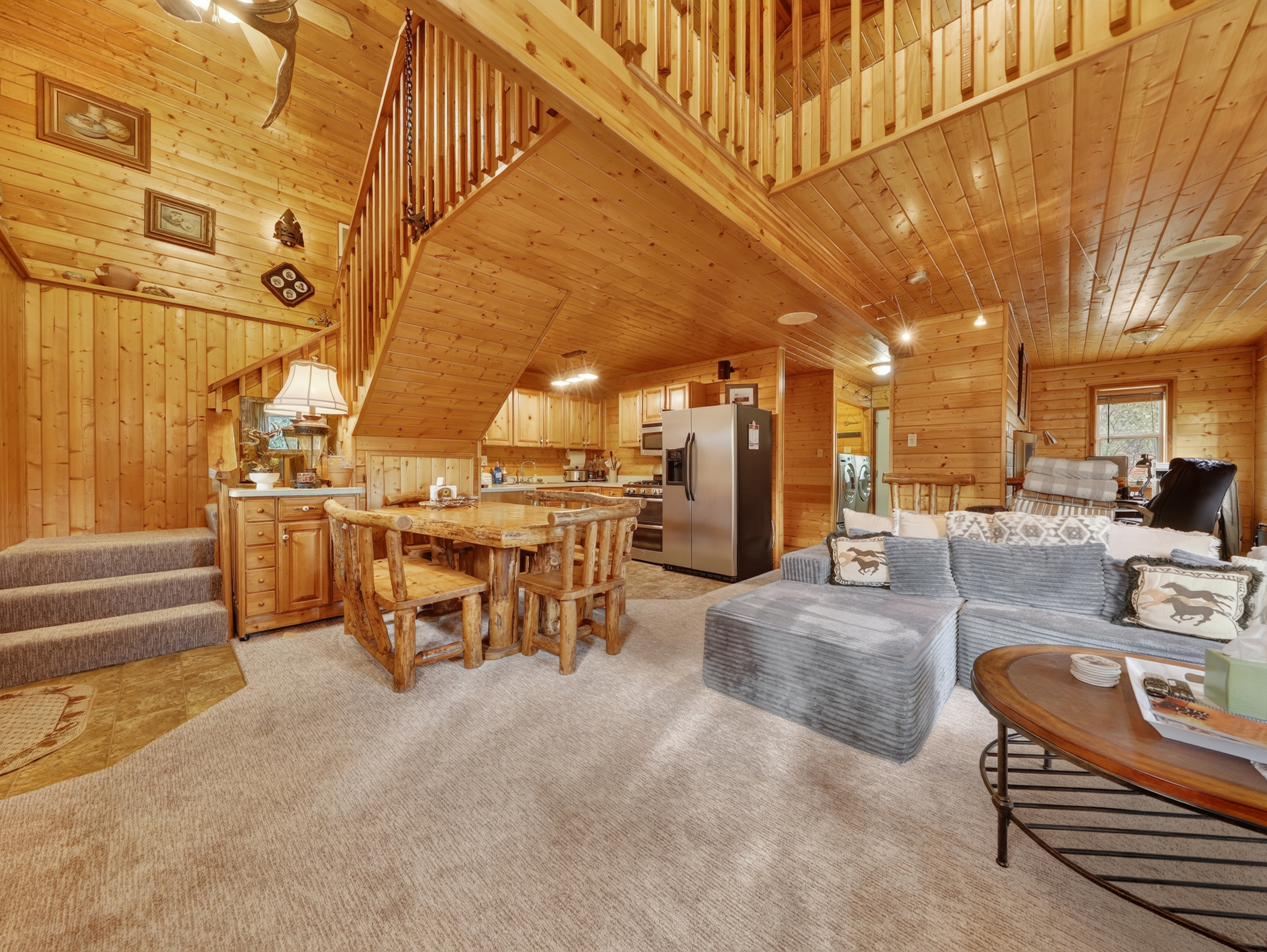 Cozy mountain retreat featuring soaring wood-paneled ceilings, rustic log kitchen, and spacious open layout. Perfect for a memorable getaway.