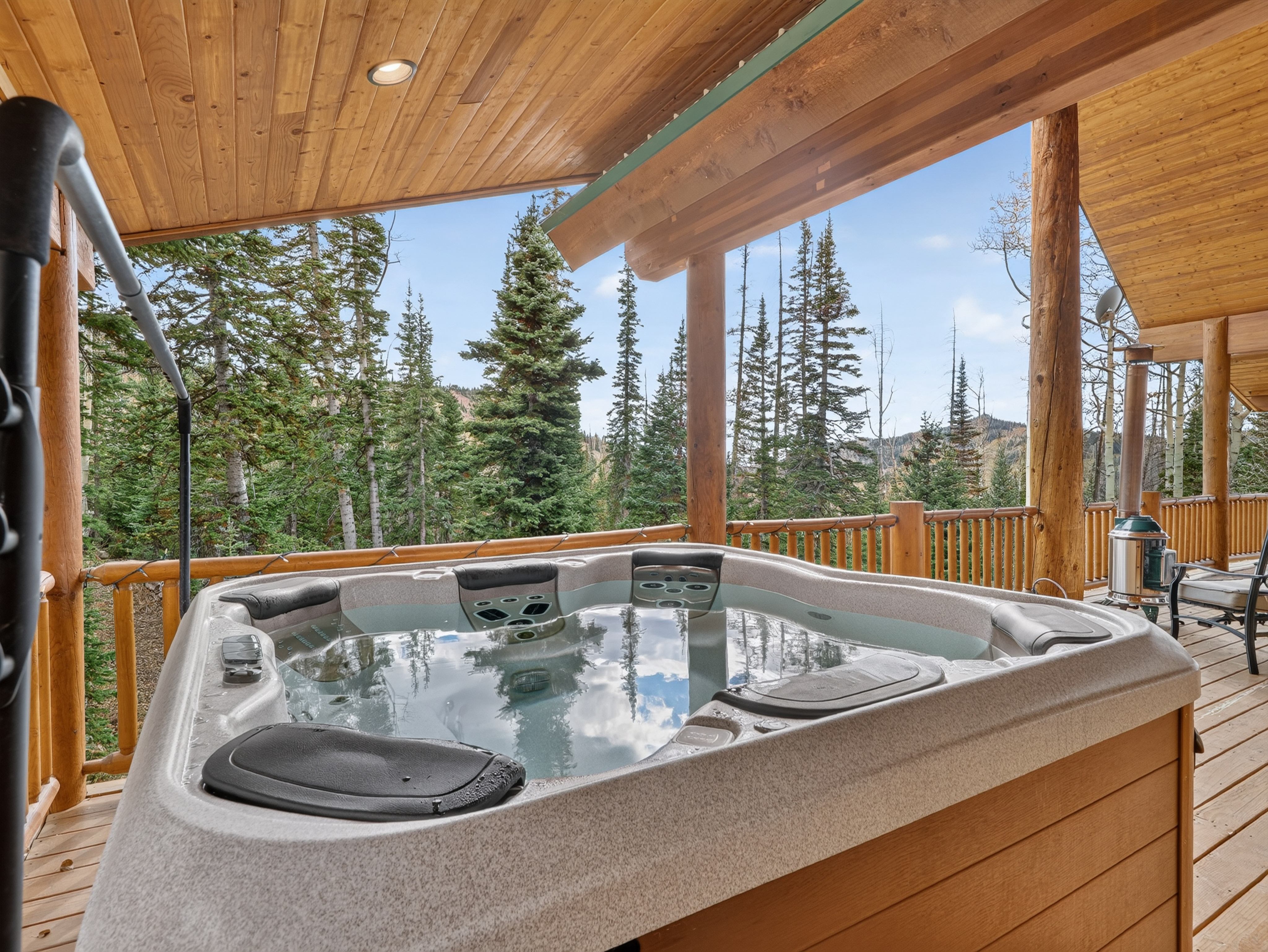 Soak in your private hot tub under a vaulted wood ceiling, where you can unwind while surrounded by towering pines and mountain views stretching into the distance.